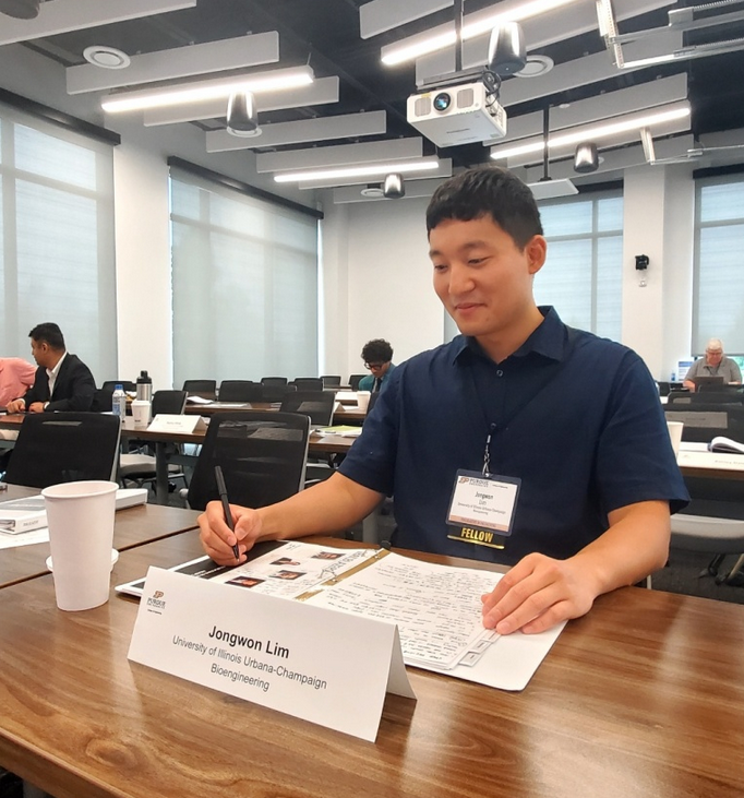 Jongwon Lim sitting at a table overlooking several papers