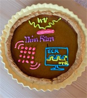 Photo of The Perry Group&rsquo;s research in baked form, made by Alexia Popescu. The square represents the thin films which the Perry group prepares by pulsed laser deposition, the alternating waves show the electrical/optical relaxation of defects, and the dots represent the changing atomic lattice.